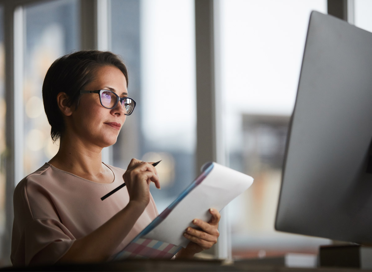 donna davanti al pc con un quaderno che prende appunti